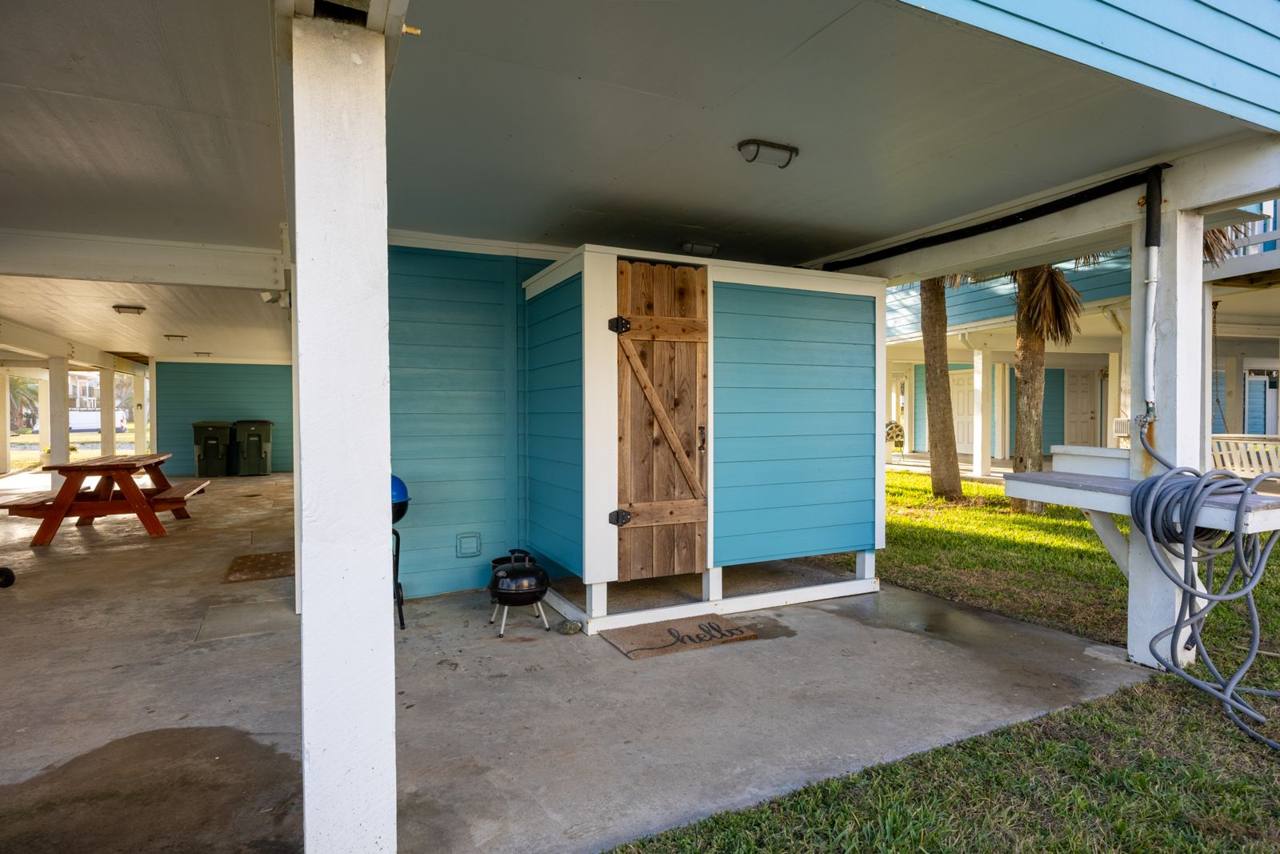Covered area under the house with a picnic table, charcoal grills and an outdoor shower