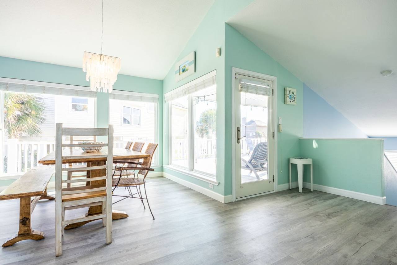 Bright dining area with a vaulted ceiling and a door out to the deck