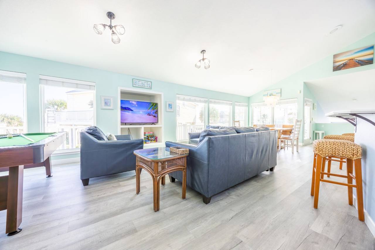 Living area with leather seating, a TV and the pool table, with the dining area beyond