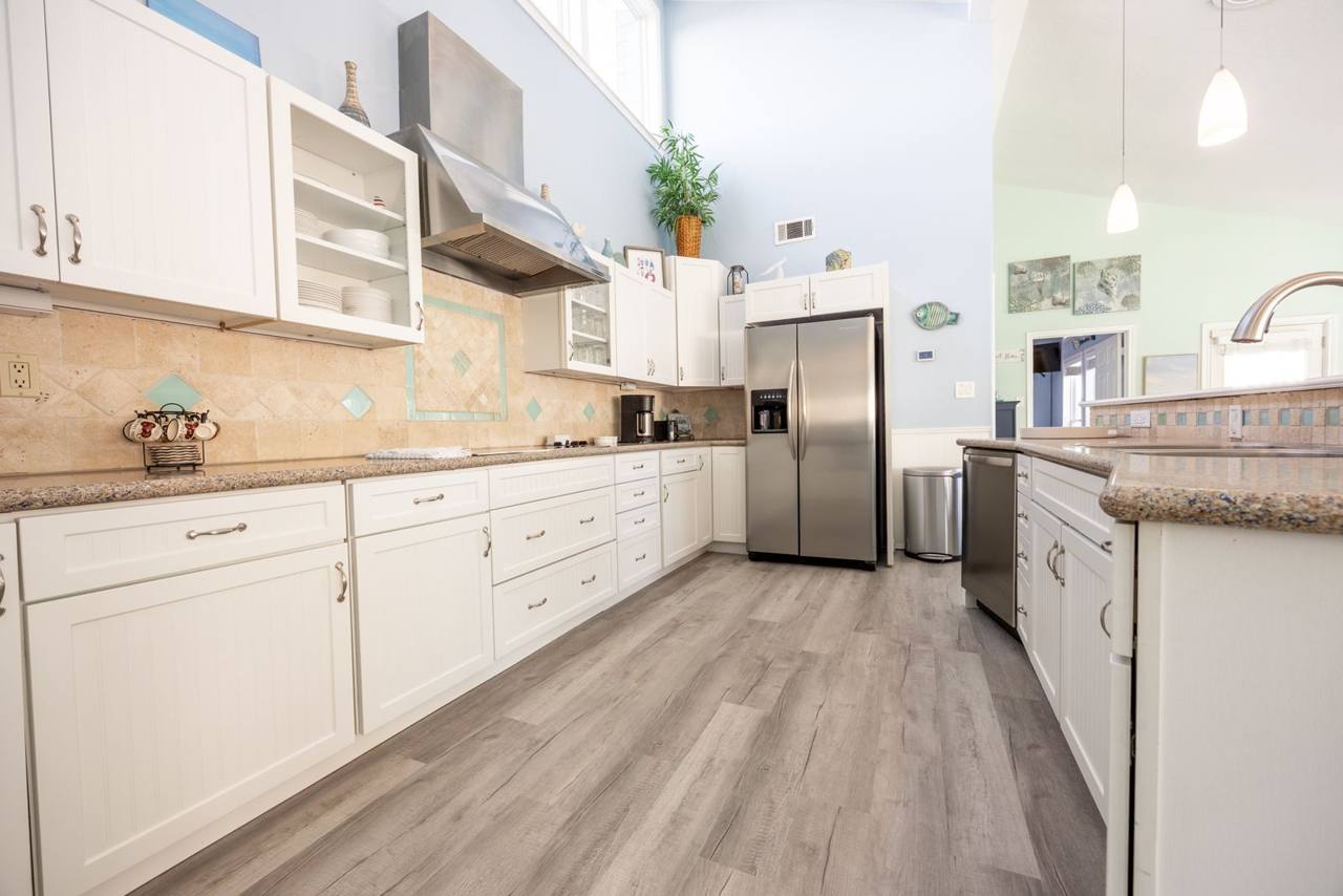 Kitchen with a stainless refrigerator, dishwasher, coffee maker and shelves of dishes