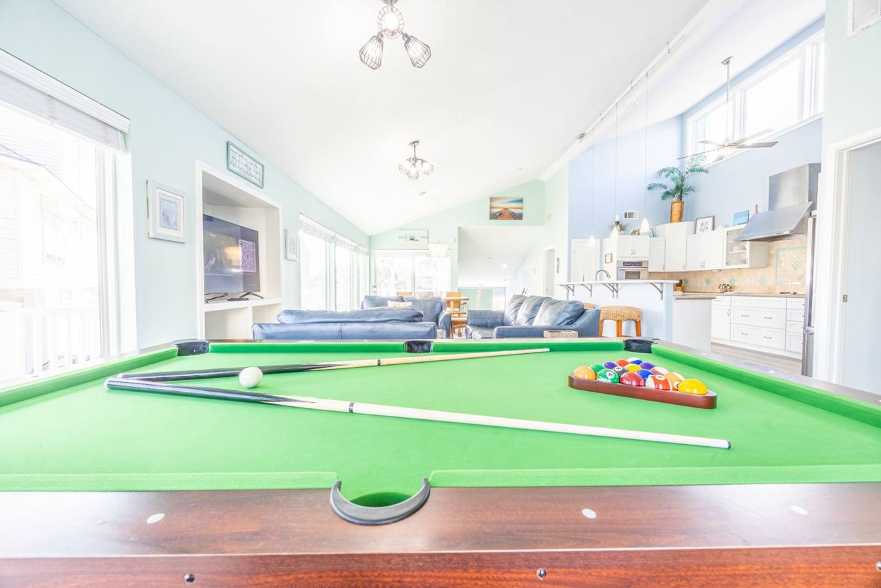 Pool table with the living room and kitchen beyond