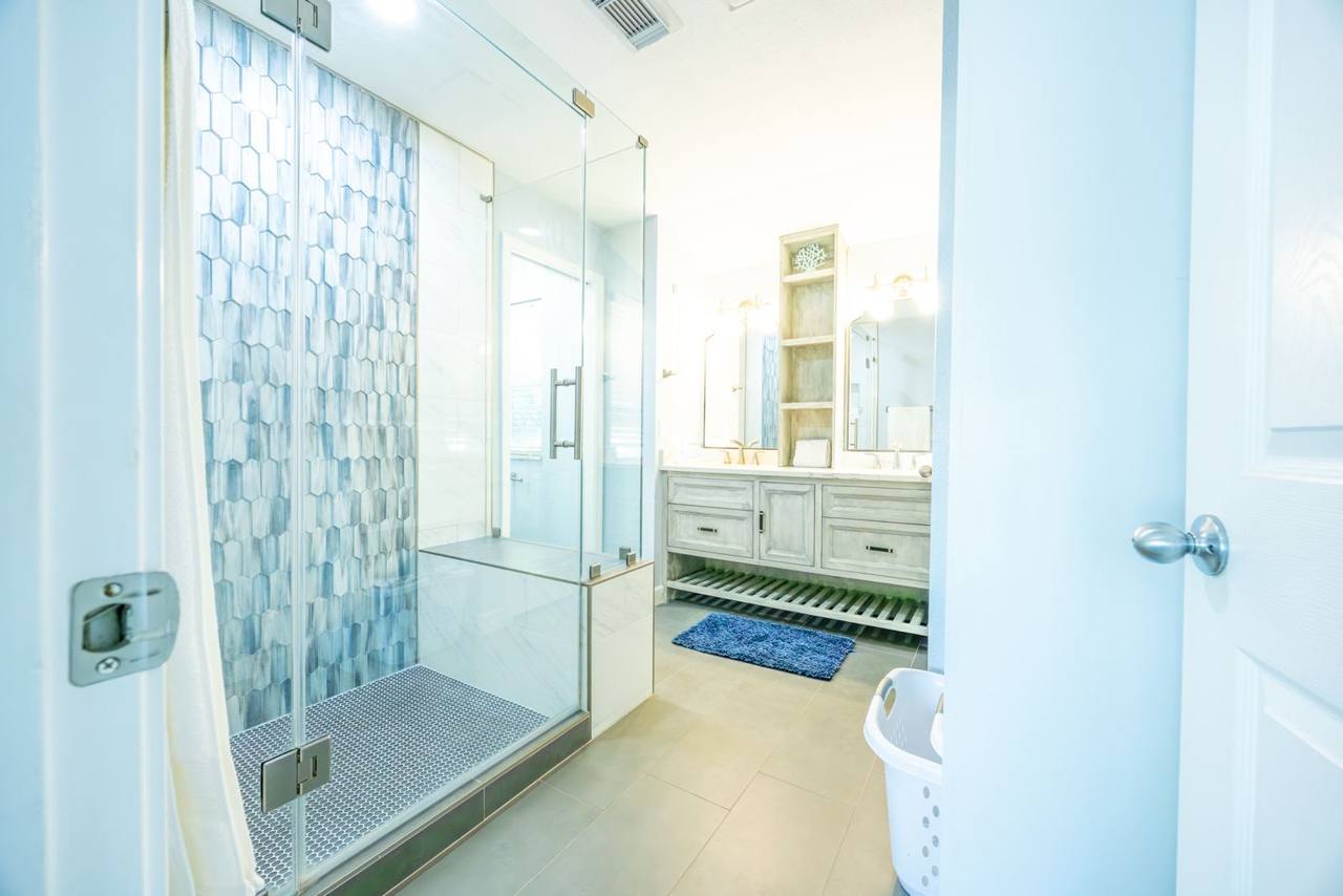 Bathroom with a walk-in glass shower with a bench and a double vanity