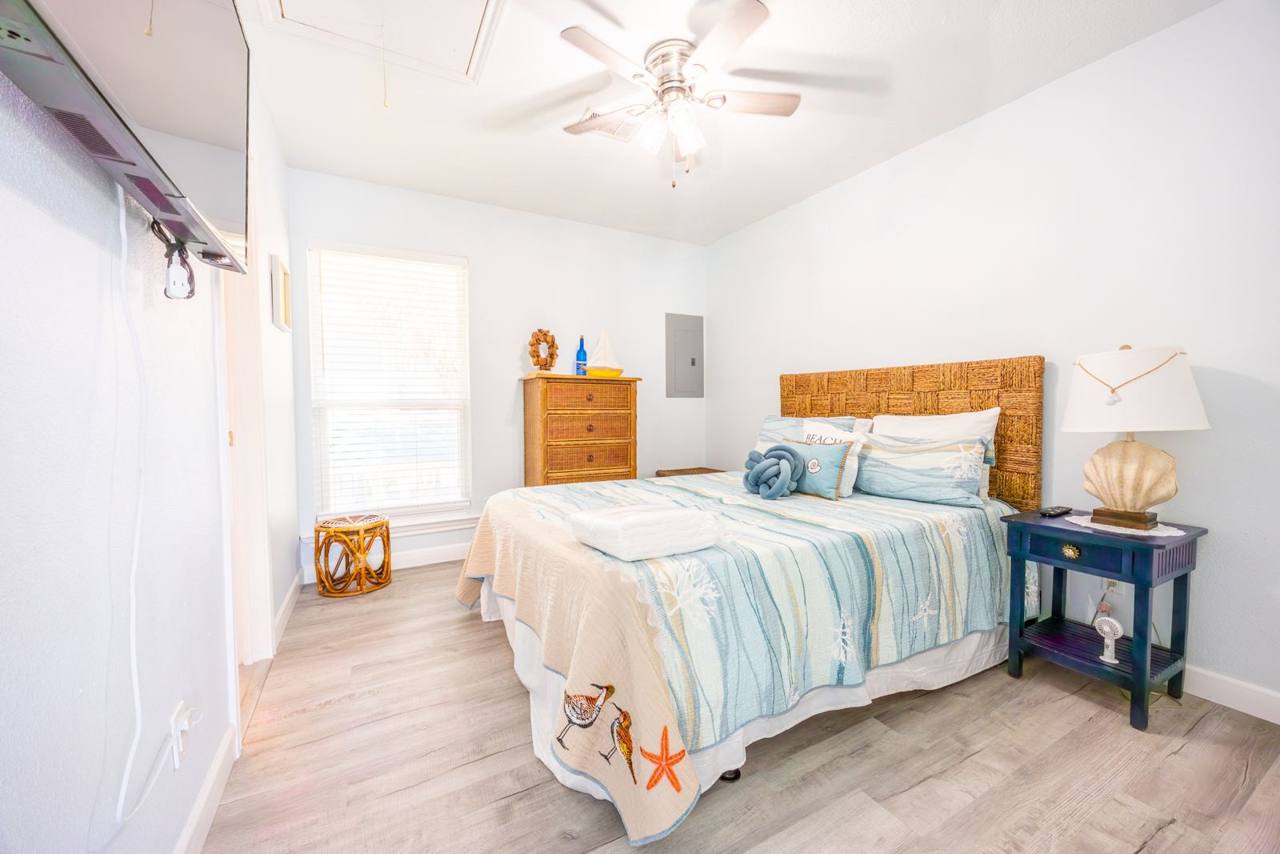 Second bedroom with coastal bedding, a wall-mounted TV and a ceiling fan