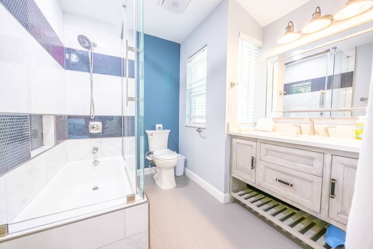 Second bathroom with a tub-shower, glass door and wood-look vanity